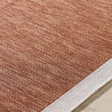 Close-up of the Chetan Brown Outdoor Rug showing its woven texture and brown, burnt orange, and cream colors. Texture