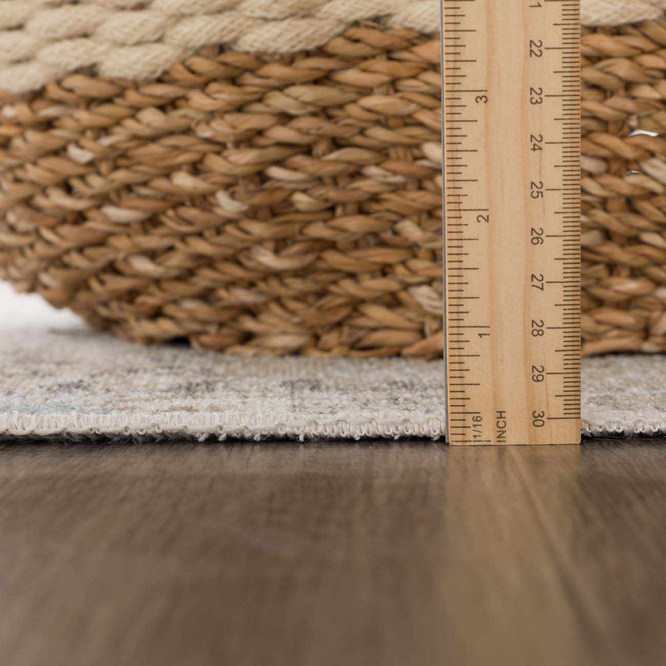 Close-up of Beige Holi-4600 Washable Area Rug edge with ruler, showing pile height next to a woven basket. Pile