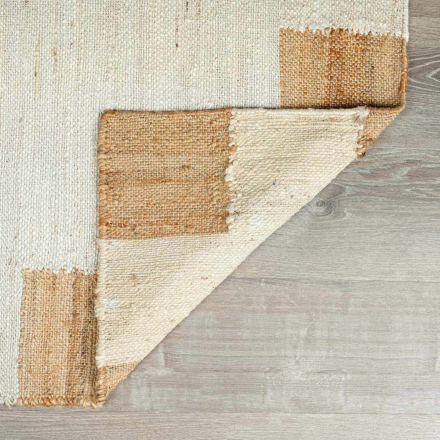 Close up of the hand woven Rocio White Jute Carpet showing its cream and tan color block design and textured jute fibers. Fold
