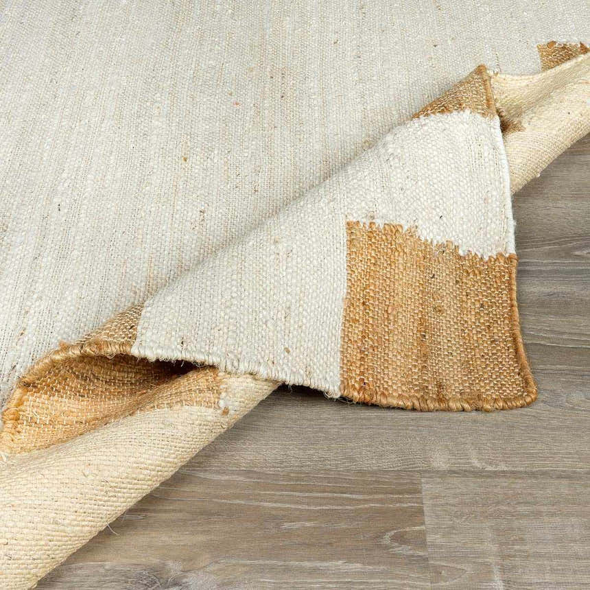 Close-up of the hand-woven Rocio White Jute Carpet showing cream and tan colors and natural fiber texture. Fold