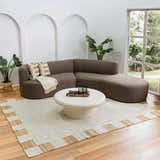 Living room scene with a Rocio White Jute Carpet, brown sectional sofa, and round coffee table. Neutral, modern aesthetic. Roomscene-Rectangle