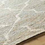 Close-up of the hand woven Damawato Jute Carpet. Beige, gray, and natural jute fibers create a textured, geometric pattern. Pile