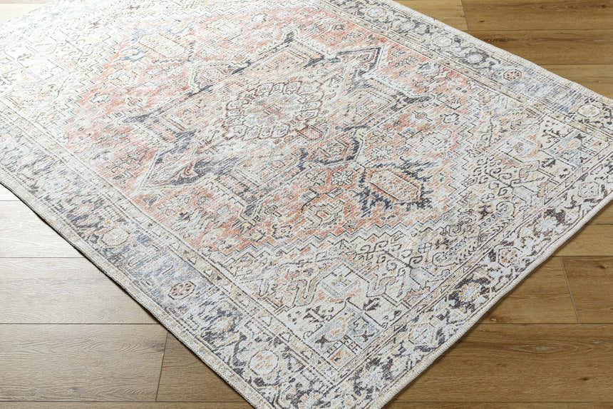 Close-up of the Aethwy Washable Area Rug. Farmhouse style rug in light silver, prairie dust, and silver gray on wood floor. Corner