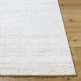 Close-up of the white Arlind Area Rug showing its plush shag texture on a light wood floor. Front