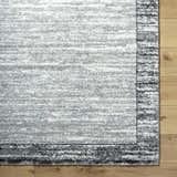 Close up of the Dhaval Black Area Rug showing its light gray, charcoal, and black colors with a subtle pattern. Corner