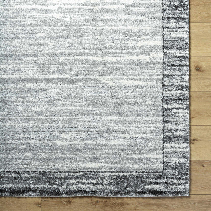 Close up of the Dhaval Black Area Rug showing its light gray, charcoal, and black colors with a subtle pattern. Corner