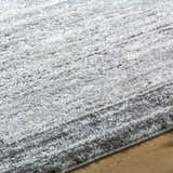Close-up of the textured Dhaval Black Area Rug with black, charcoal, and light gray hues on a wood floor. Texture