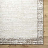 Close-up of the Dhaval Ivory Area Rug showing its cream color, soft texture, and light brown border on wood flooring. Corner