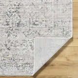 Close-up of the Alivia Area Rug showing charcoal, gray, and ivory tones. Traditional farmhouse style rug with folded corner. Fold