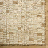 Close-up of the hand-tufted Anusha Area Rug. Beige and tan wool rug with a contemporary geometric design. Corner
