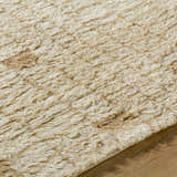 Close up of the hand-tufted Anusha Area Rug. Beige and tan wool fibers create a soft, textured look. Texture