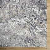 Close-up of the Aolani Medium Gray Area Rug showing its abstract black, gray, ivory, and tan pattern and textured weave. Corner