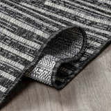 Close-up of the Stephan Area Rug showing its black, charcoal, and cream striped pattern and woven texture. Fold