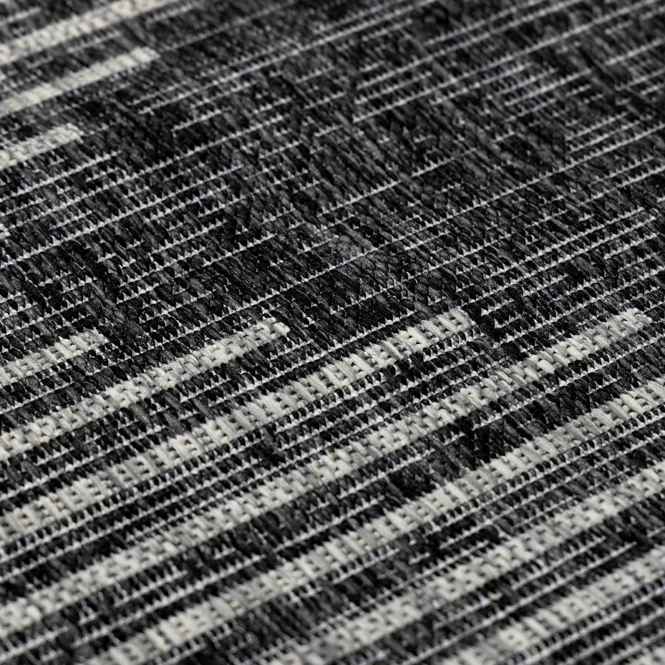 Close-up of the Stephan Area Rug showing a black, charcoal, and cream contemporary striped pattern and woven texture. Texture