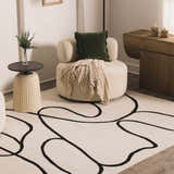 Living room scene with bone Eilir Modern Boho Rug, round chair, and side table. Black abstract lines on the rug add a modern touch. Roomscene-Rectangle