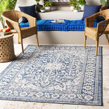 Outdoor patio scene with wicker chairs and blue cushions, featuring the Etoile Navy Blue Performance Rug. Roomscene-Rectangle