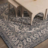 Close-up of the Etoile Navy Blue Performance Rug with a traditional floral pattern and neutral border under a light wood table. Roomscene-Rectangle