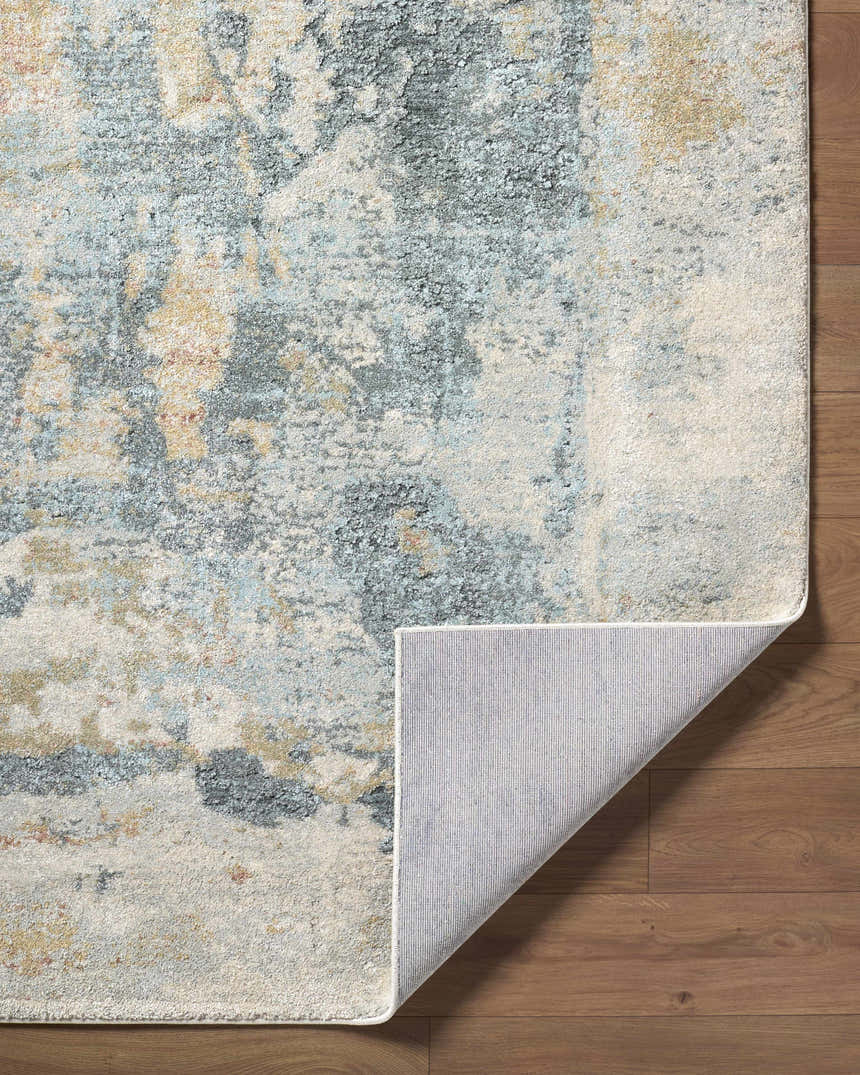 Close-up of the Alanna Thick Luxe Area Rug showing its beige, gray, and pale blue contemporary design and machine woven texture. Fold