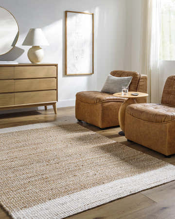 Living room scene with tan leather chairs and Aderyn Jute Area Rug in camel and pearl on wood floor. Roomscene-Rectangle