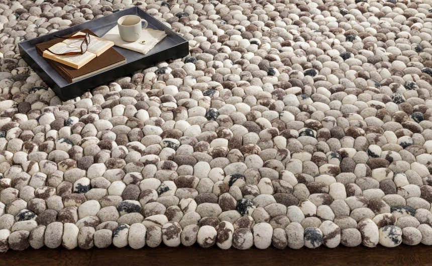 Close-up of the hand woven Fillmore Area Carpet. Wool rug with black, charcoal, cream, and gray pebble design. Styleshot
