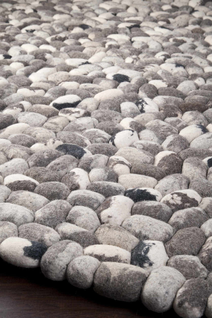 Close up of the hand woven Fillmore Area Carpet. Wool rug features black, charcoal, cream, and gray tones. Styleshot