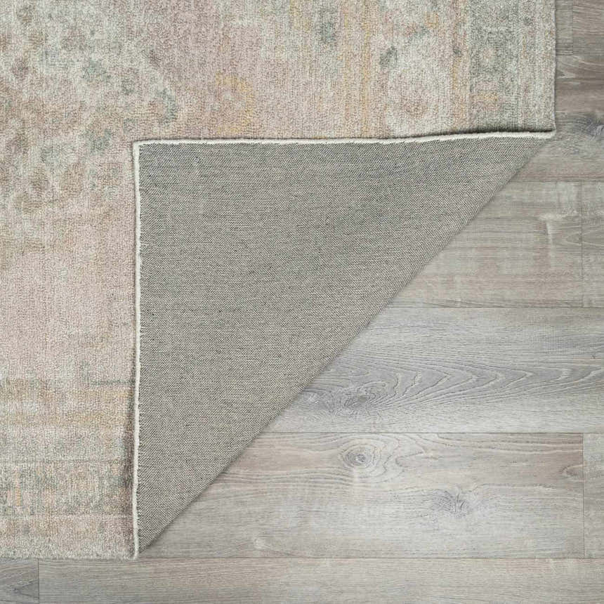 Close-up of the Luciana Handmade Galey Alix x LIVABLISS rug, showing the backing and the antique gold, rose, and sage colors. Fold