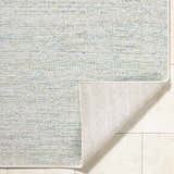 Close-up of the Alezae Ivory Area Rug showing its woven texture and ivory, light gray, and pale blue colors. Fold