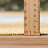 Close-up of the Djugun Yellow Outdoor Rug showing pile height with a ruler, revealing its texture and construction. Pile