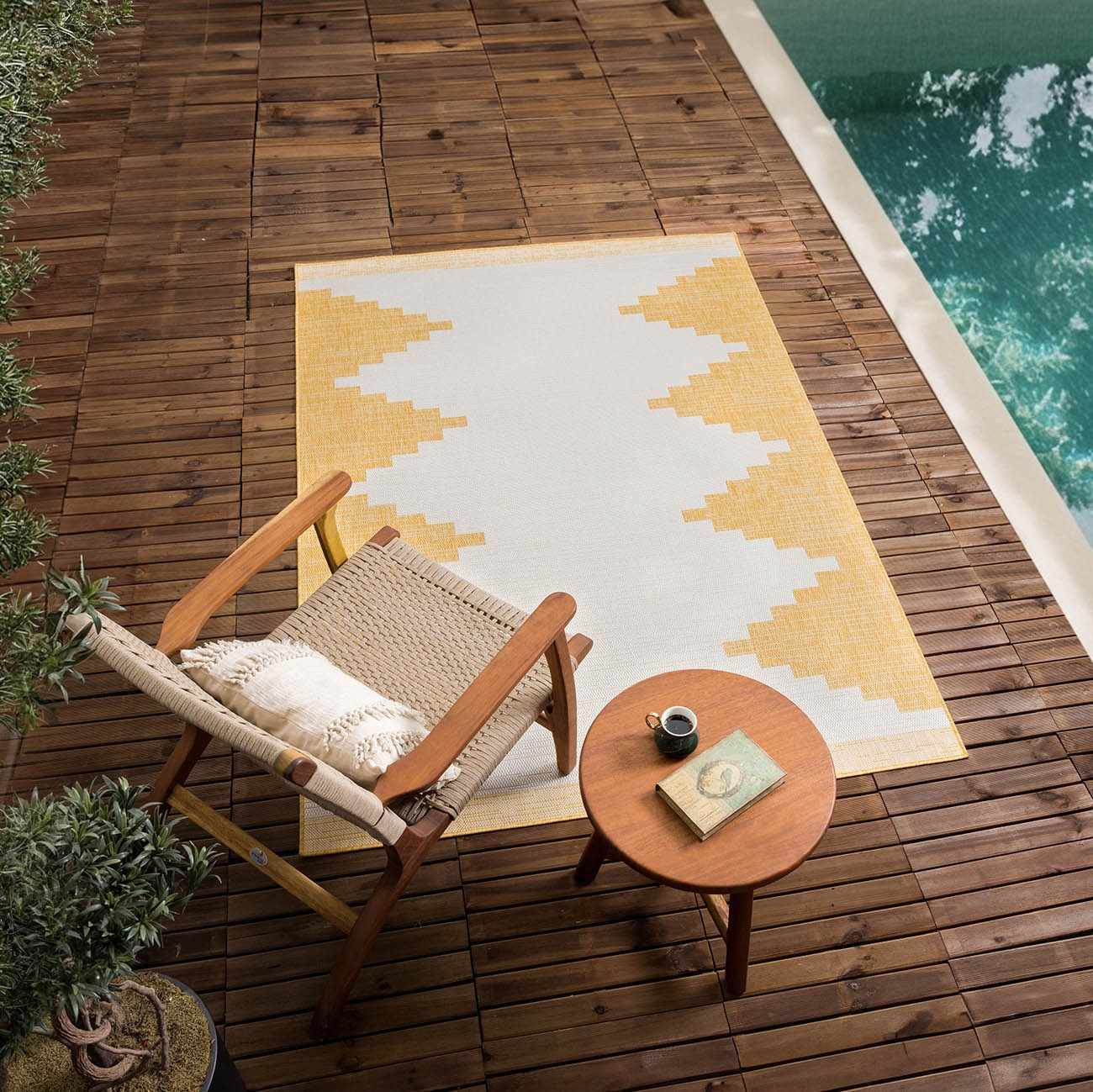 Outdoor scene with Djugun Yellow rug, chair, and side table on a wood deck near a pool. Roomscene-Rectangle