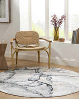 Bright reading nook with a round Fremantle Gray Marble Rug, woven chair, and natural wood accents. Roomscene-Round