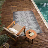 Outdoor scene with Frankville Black&White rug on wood deck near pool. Chair, table, book, and coffee create a relaxing vibe. Roomscene-Rectangle