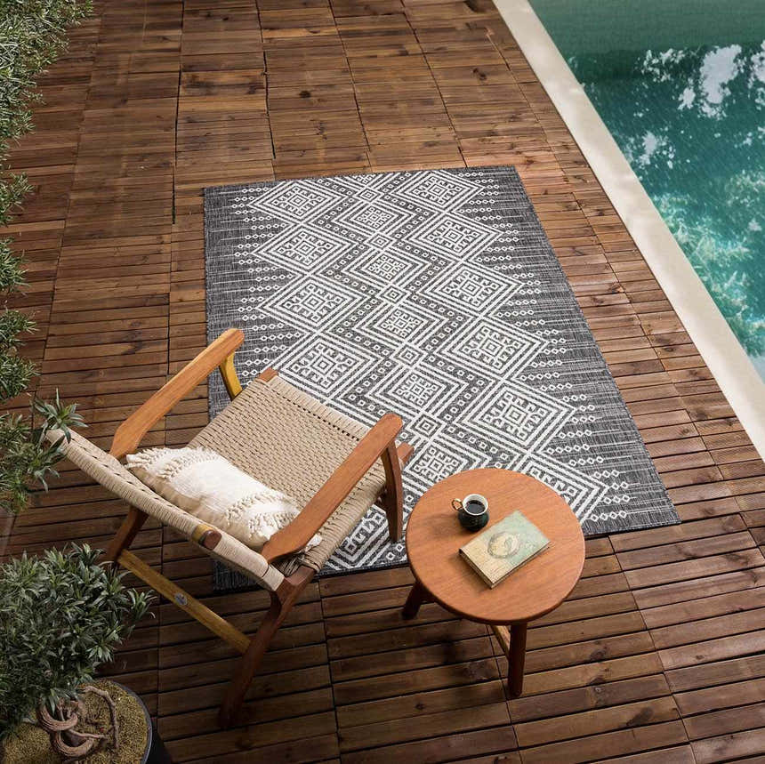 Outdoor scene with Frankville Black&White rug on wood deck near pool. Chair, table, book, and coffee create a relaxing vibe. Roomscene-Rectangle