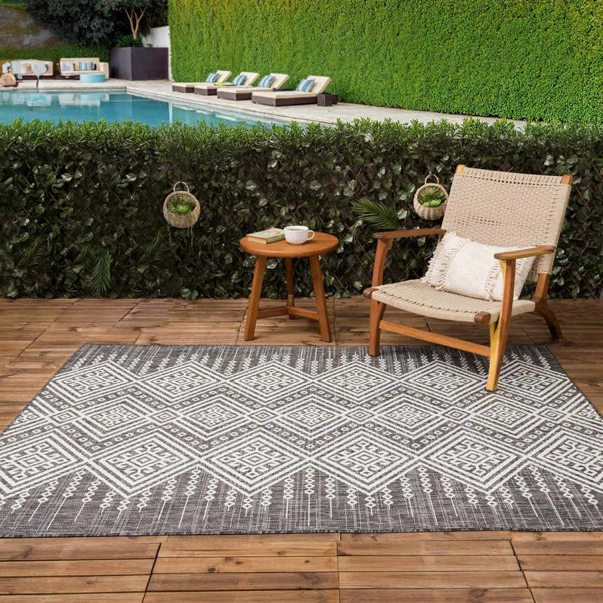 Outdoor poolside patio with a Frankville Black&White rug, chair, and small table. Roomscene-Rectangle