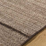 Close-up of the hand woven Lisua Global Modern wool rug, showing texture and neutral brown color. Texture