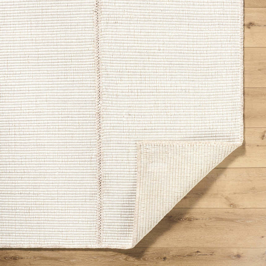 Close-up of the hand woven Xowi Global Modern Wool Area Rug, showcasing its neutral color, subtle texture, and braided edge detail. Fold