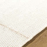 Close-up of the hand woven texture of the Xowi Global Modern Wool Area Rug in cream, on wood flooring. Texture