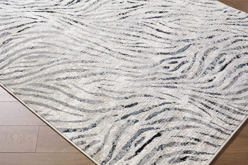 Close-up of the Arlene Area Rug. Contemporary style rug with black, cream, and gray wavy pattern. 60% Polyester. Corner
