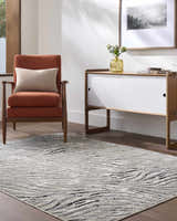 Living room scene with an Arlene Area Rug in black, cream, and gray. Contemporary style with an orange chair and modern cabinet. Roomscene-Rectangle