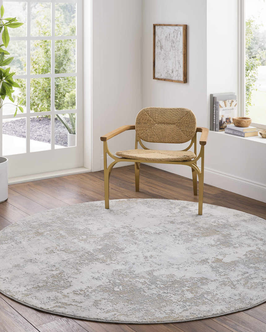 Bright room scene with a round, beige Ganit Thick Luxe Boutique Rug under a woven chair. Roomscene-Round