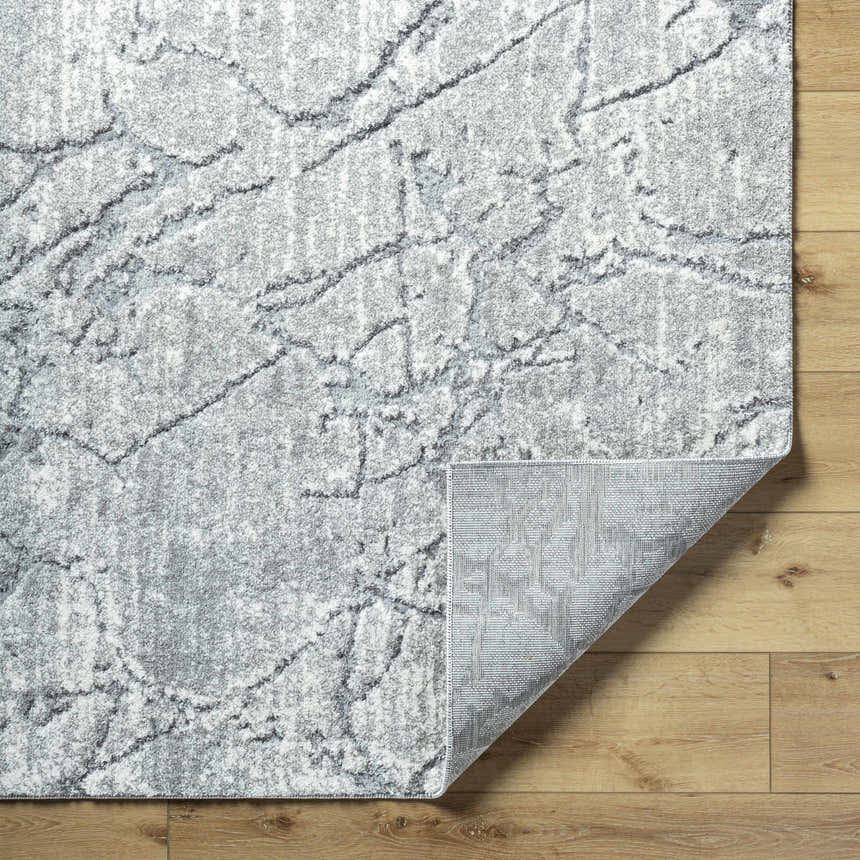 Close-up of the Genkei Black Area Rug showing its charcoal, light gray, and white abstract pattern and machine-woven texture. Fold