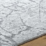 Close up of the Genkei Black Area Rug, showing its light gray, charcoal, and black geometric pattern and soft texture. Texture