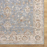 Close-up of the Avivit Sage Area Rug. Traditional floral design in blue, cream, tan, and gray on a wood floor. Corner