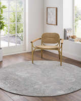 Bright room featuring a round Gilmanton Thick Luxe Boutique Rug in dusty sage and gray under a woven chair. Roomscene-Round