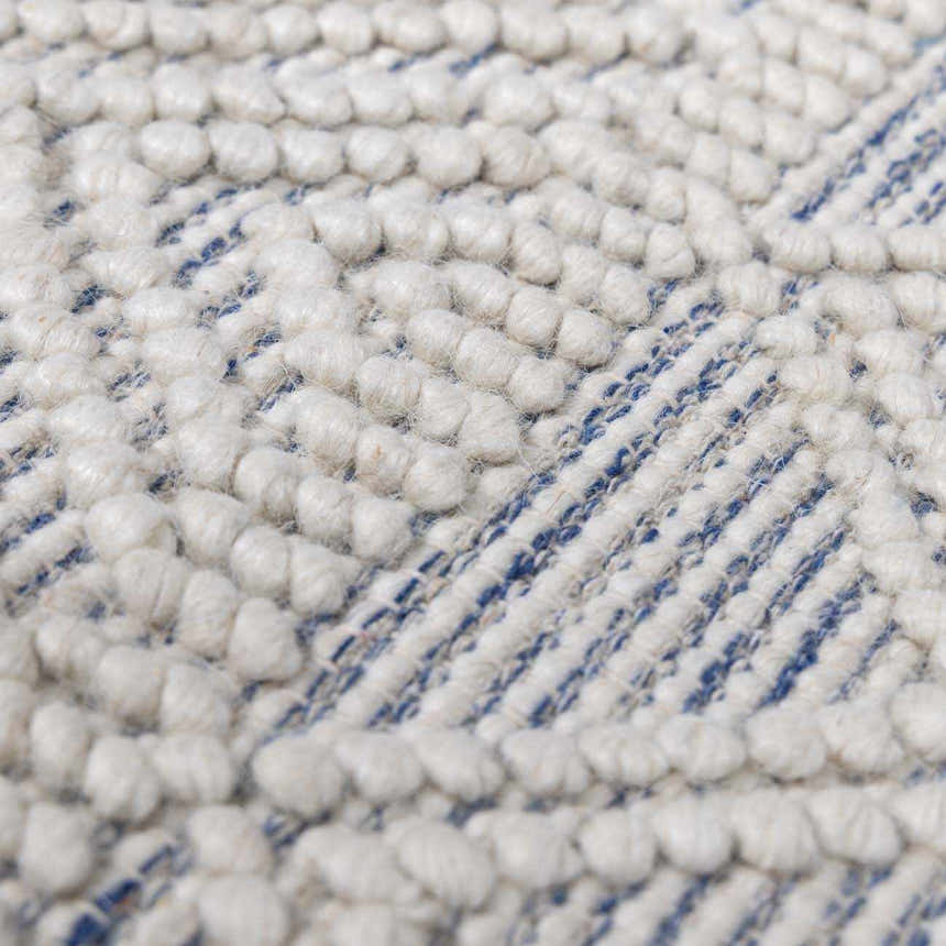 Close-up of the Ginter Handmade Beige Wool Rug showing its textured, hand-woven design in ivory and blue. Texture
