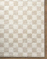 Close-up of the Gallicchio Area Rug. The rug has a checkerboard pattern in ivory and beige. Corner
