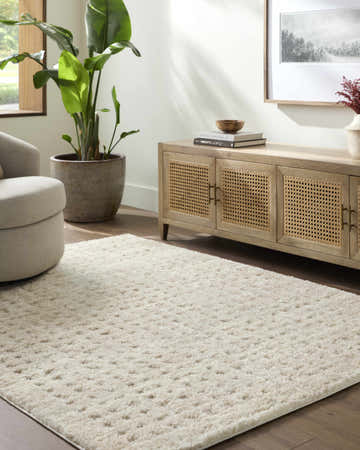 Living room scene with a cream Armand Luxe Shag Rug, light wood media console, and neutral swivel chair. Roomscene-Rectangle