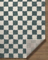 Close-up of the Goianinha Area Rug. Plush, checkered pattern in ivory and teal. Machine woven polypropylene rug. Fold