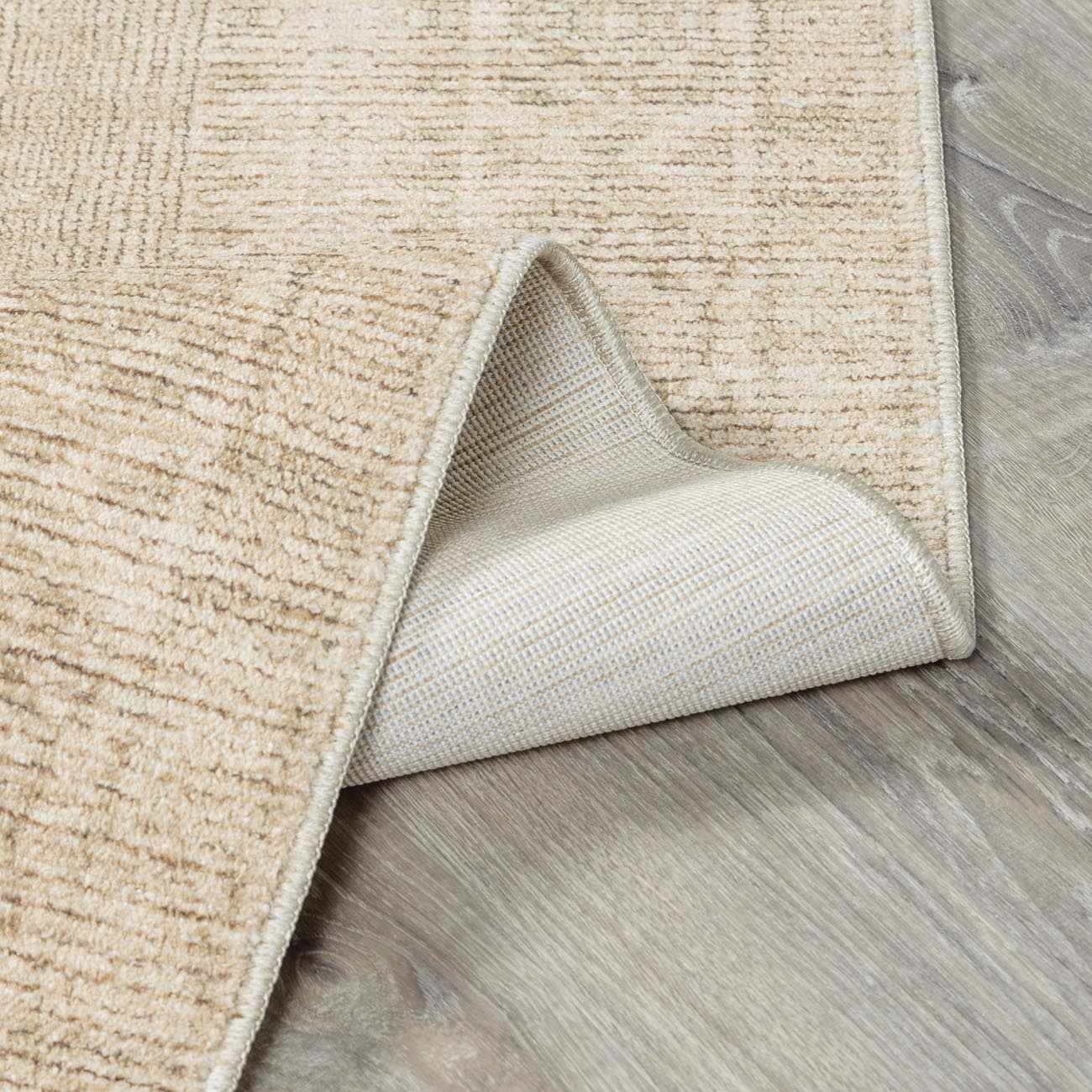 Close-up of Fetscher IV Vintage Damask Area Rug showing light brown, olive, and peach tones with a textured, woven design. Fold