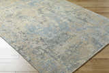 Close-up of the Greenhills Handmade Wool Area Rug. Beige, blue, and gray contemporary rug on hardwood floor. Corner