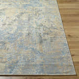 Close-up of the Greenhills Handmade Wool Area Rug, showcasing its beige, blue, and gray contemporary pattern on wood floors. Front